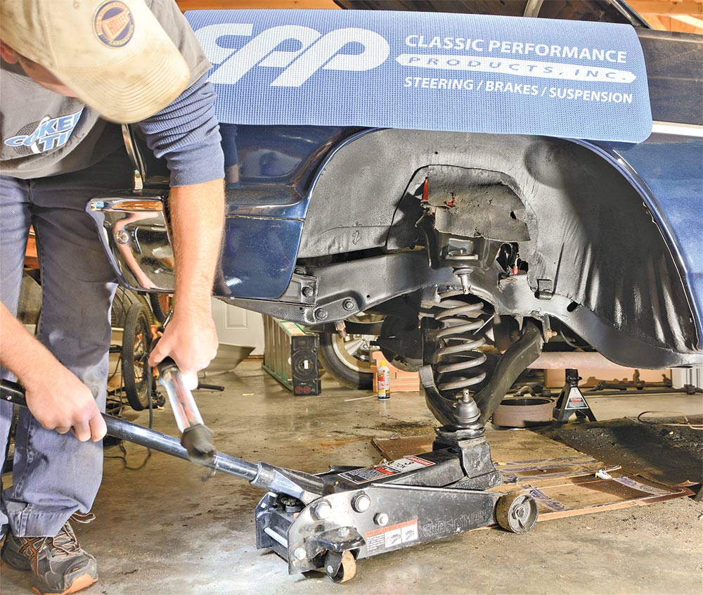 view of using a floor jack to raise the lower control arm