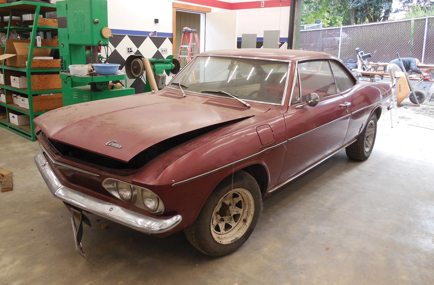 a shabby 1965 Corvair Corsa sits in a garage