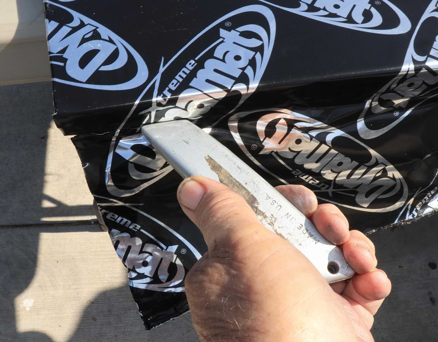 mechanic uses a matte knife with a new blade to cut the access Dynamat