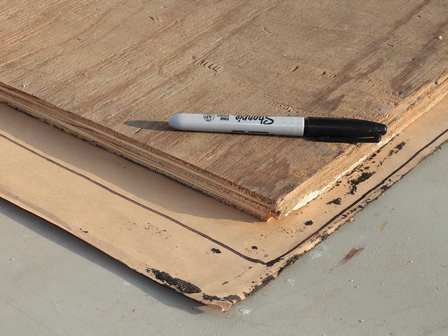 a black sharpie marker sits on uncut pieces of wood