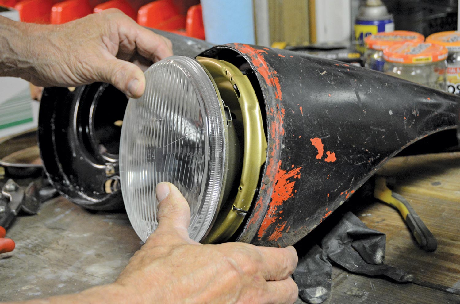 mechanic holds the headlight to the seal beam adjuster cup showing an incorrect fit