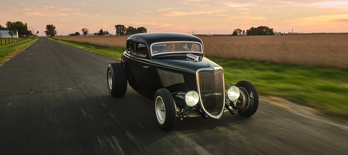 '34 Ford Coupe driving down the road in the countryside