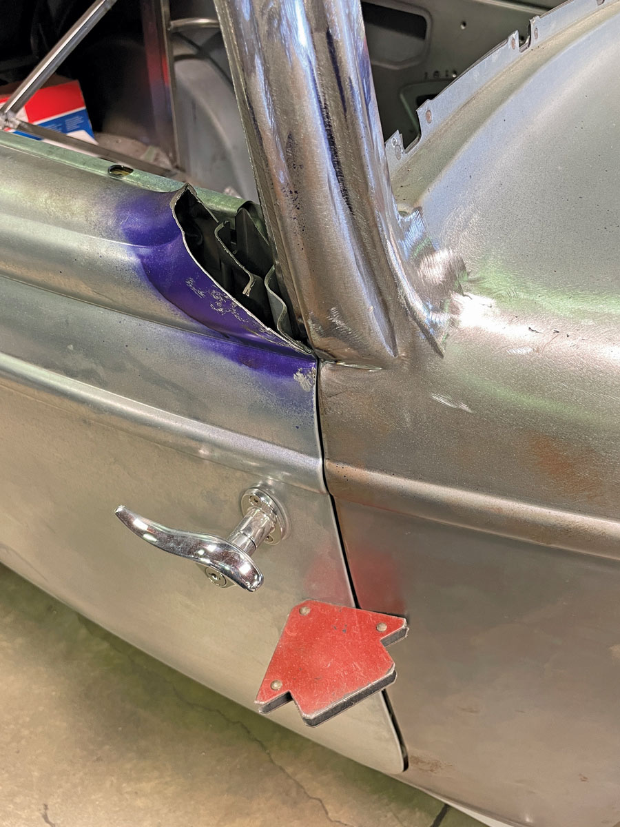 A close-up of the position of the cut in the front corner of the window down to that belt line molding. Note the use of a welding magnet to keep the door and cowl aligned.