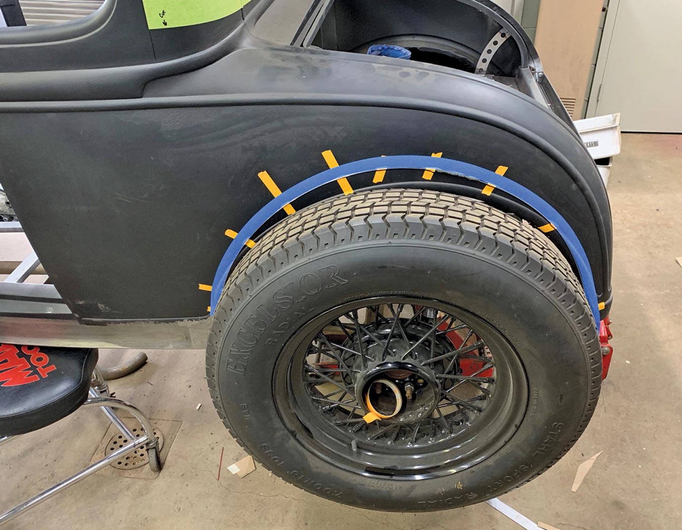 blue and yellow masking tape is used to lay out a line consistent with the curvature of the tire