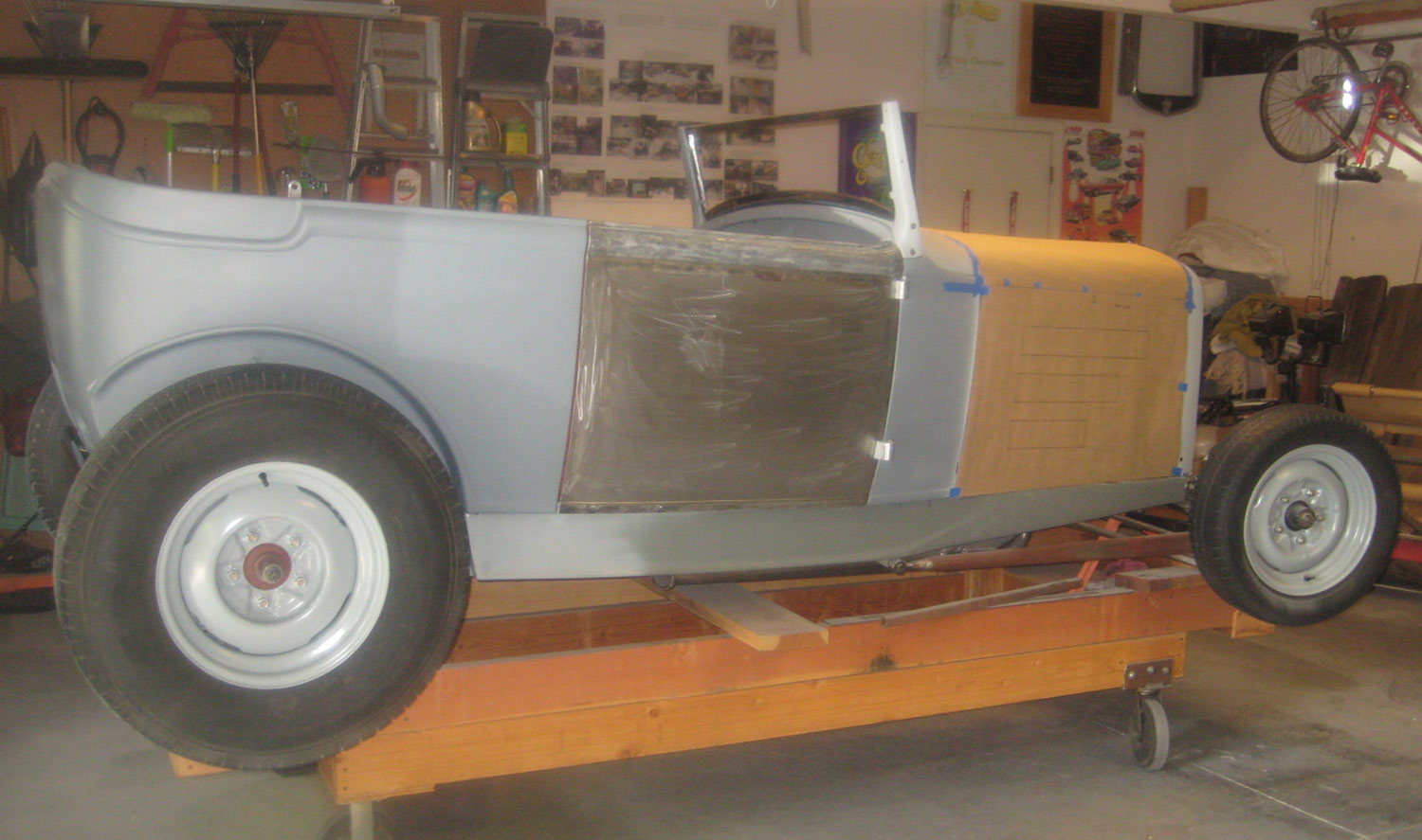 the car sits on an industrial-style dolly as the mechanic completes the final bodywork