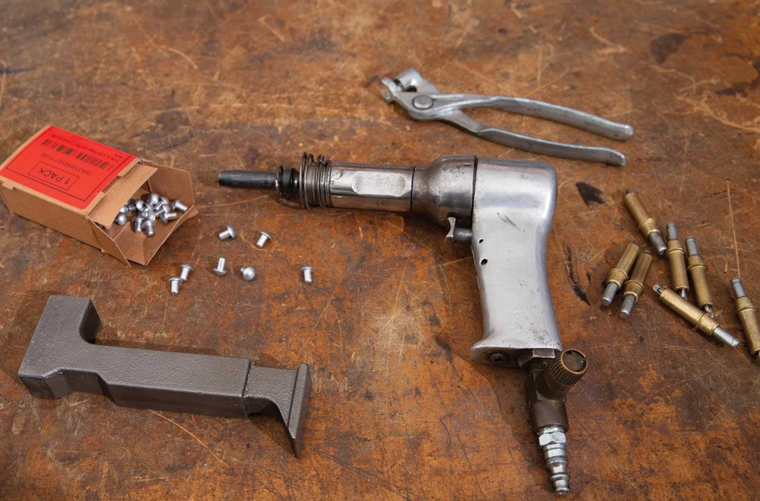 the required tools for assembly are laid out on a table, including an air hammer (PN 72819750) with control pressure regulator, 3/16-inch rivet set (PN 91010012), bucking bar (PN 9101500), 3/16-inch Clecos and Cleco tool kit (PN 9108575), and 3/16-inch rivets