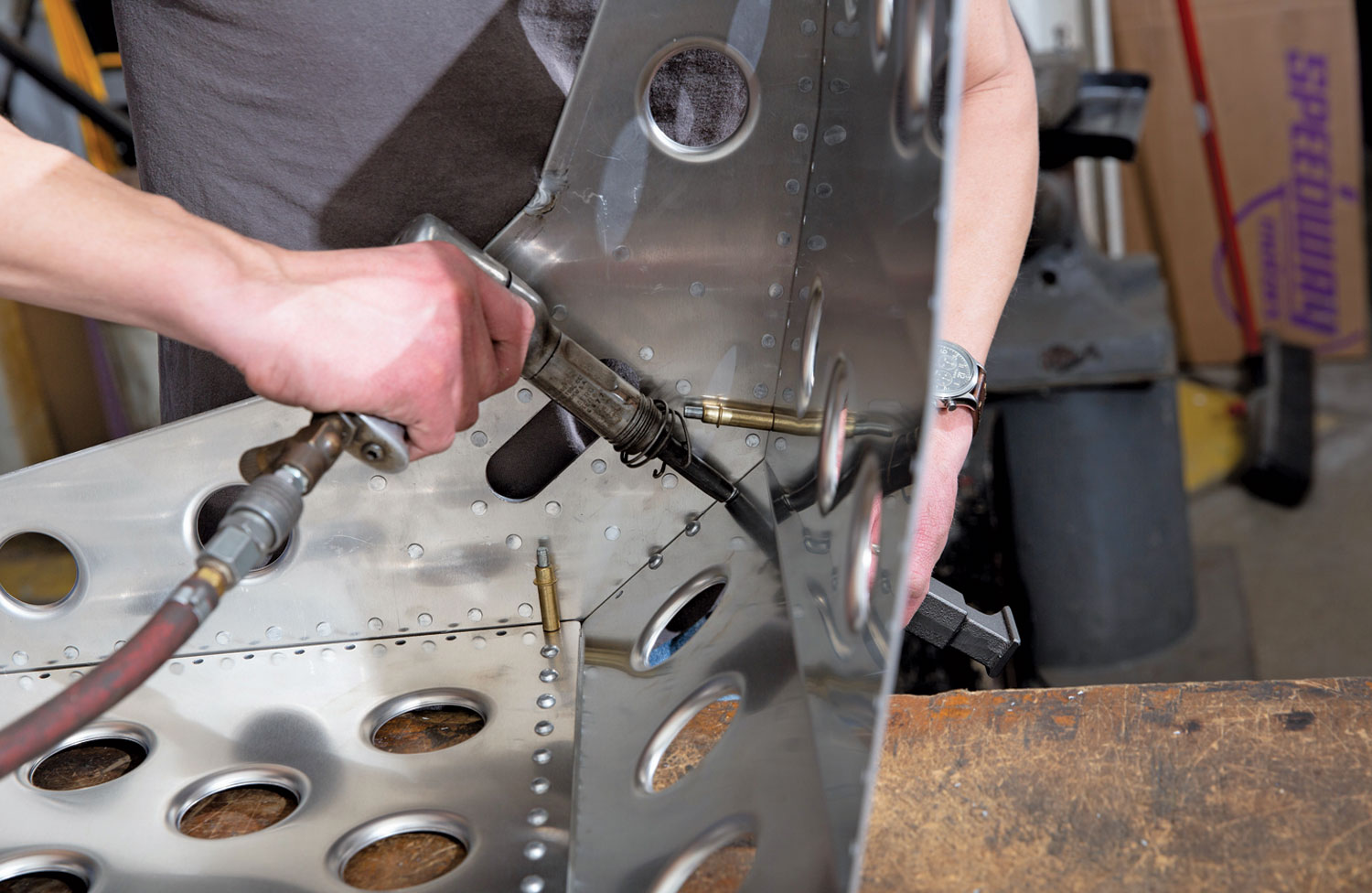 using the rivet tool and bucking bar, the mechanic begins the riveting process