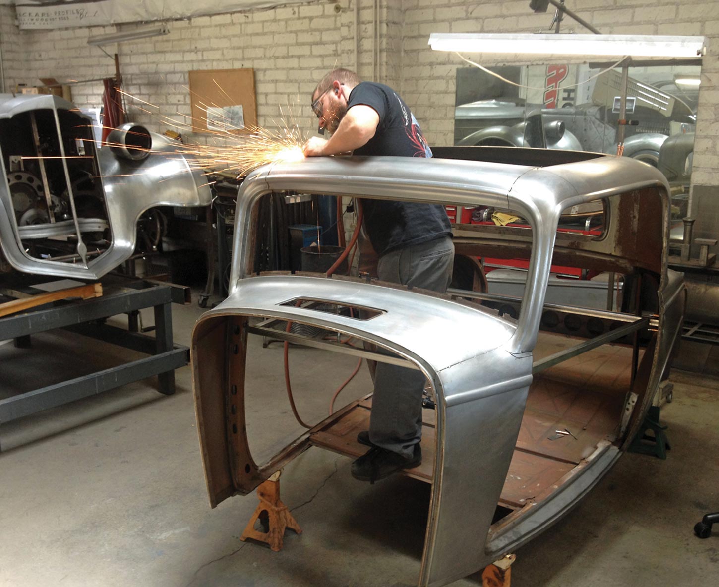 mechanic does metalwork to the sun roof opening of the Brookville Roadster body