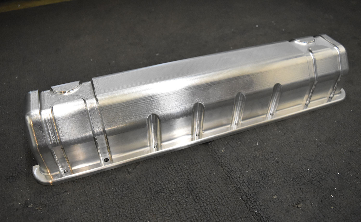 a faux valve cover, designed to replicate the look of a vintage engine, sits on a surface