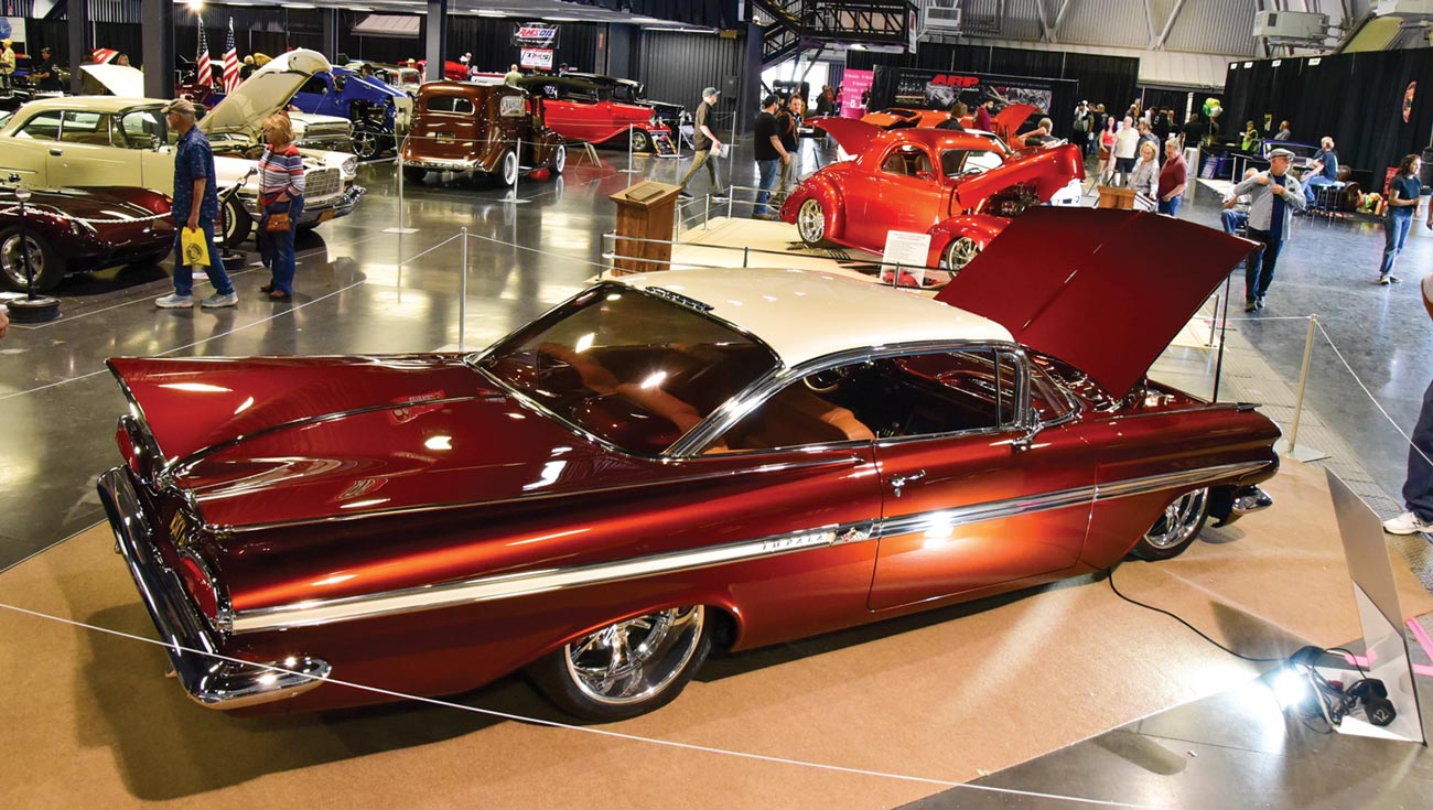 high angle, three quarter back view of a burgundy ’59 Chevy Impala with its hood open