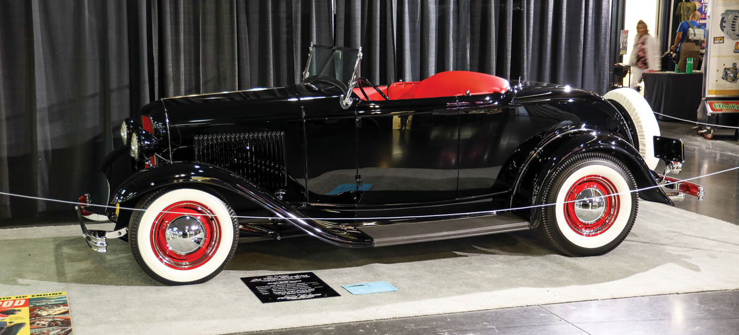 drivers side view of a black ’32 Ford roadster with Coker Classic tires and red seating
