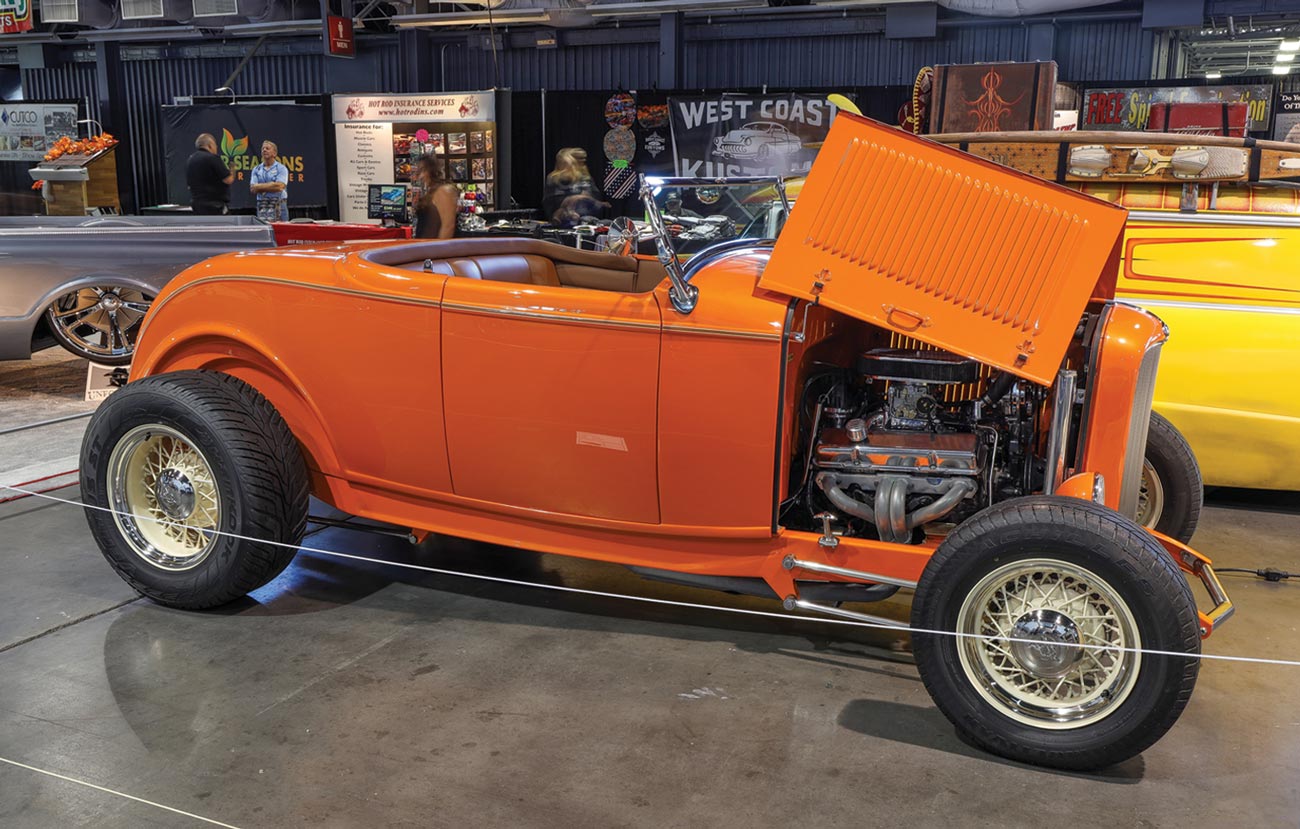 passenger side profile view of a vibrant orange Deuce roadster with its engine hood propped open