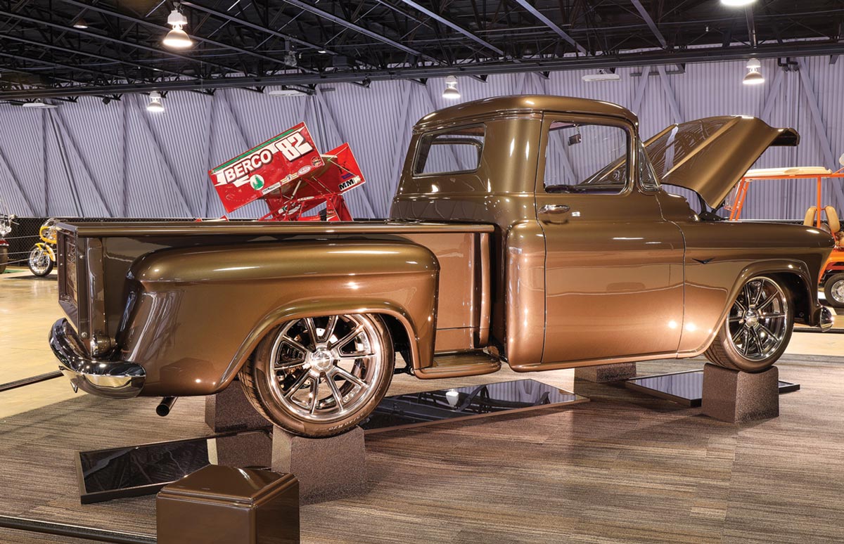 rear three quarter view of a metallic bronze ’57 Chevy pickup truck with its hood open