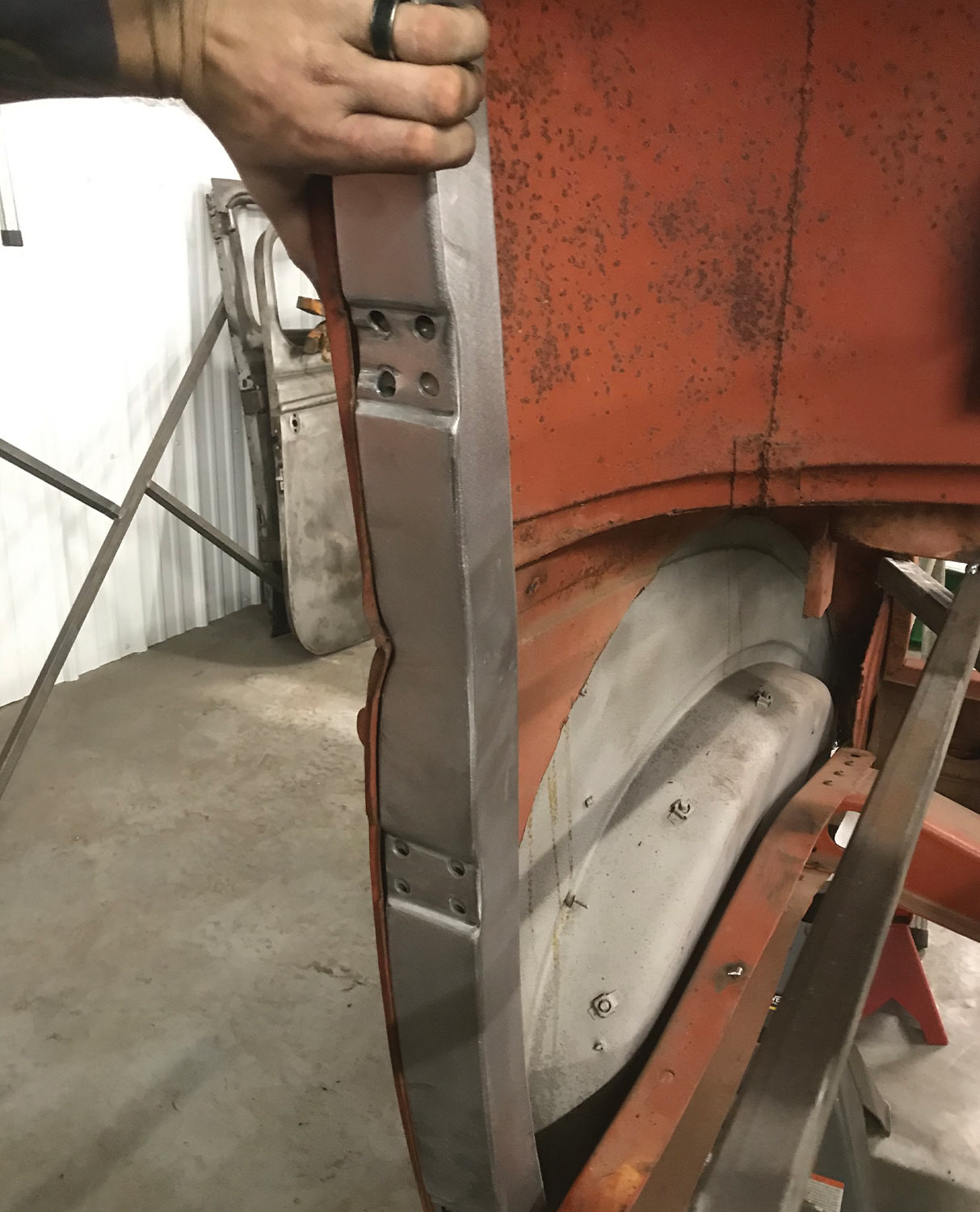 mechanic holds a new B-pillar in a door opening