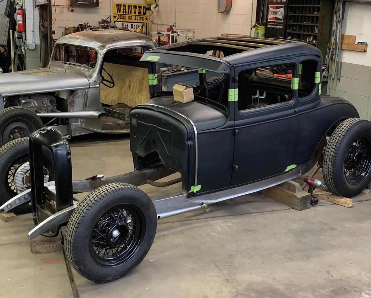 three quarter view of a matte black Model A coupe body with strips of 2-inch masking tape in prospective cut areas