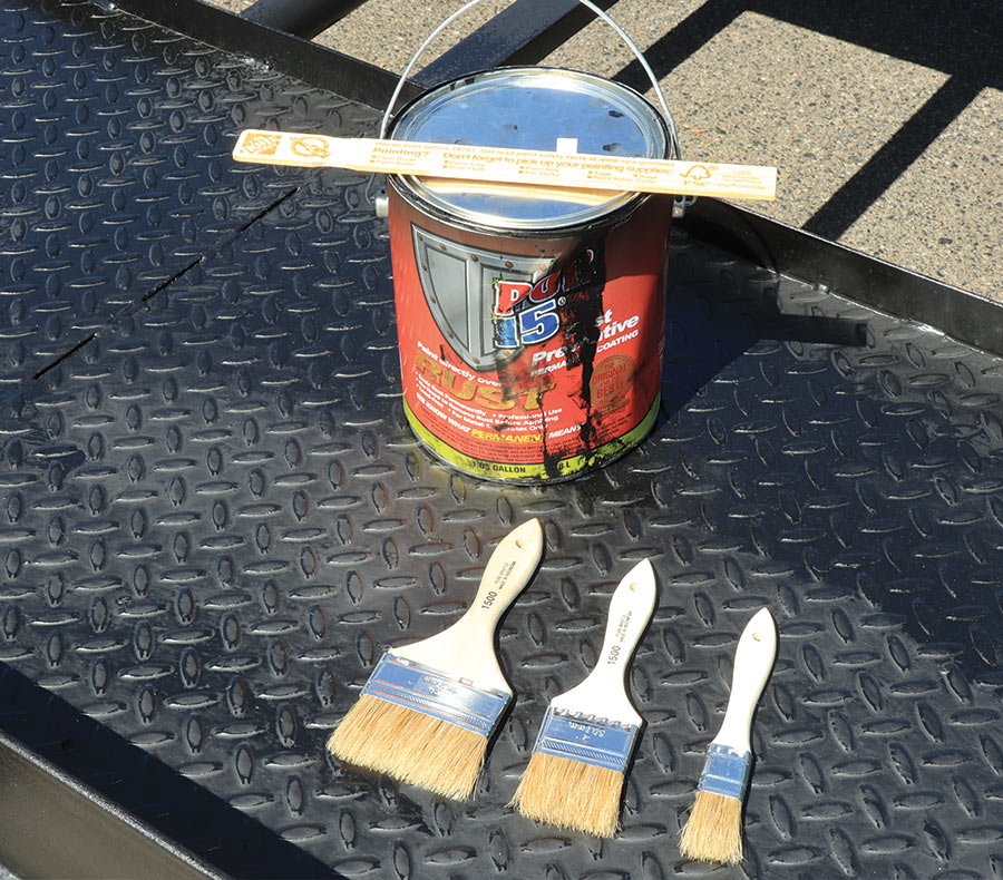 Paint can with a paint stir stick on the top and a few bristle brushes