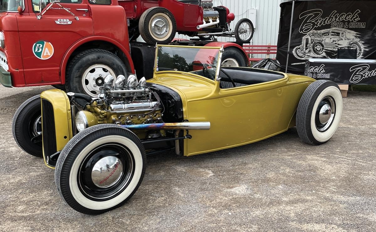 a gold Model A roadster with the top down and hood removed