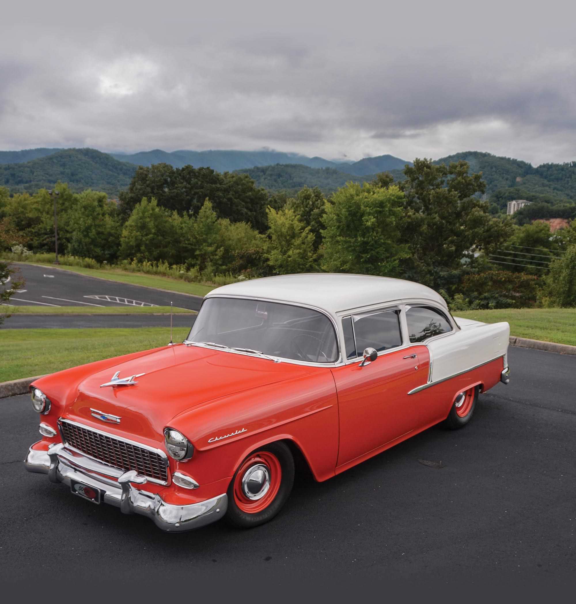 high angle three quarter view of the ’55 Chevy Delray parked against a background of green trees and hills
