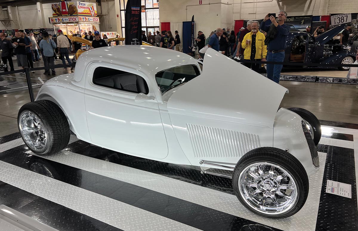 three quarter passenger side view of a white channeled and fenderless ’34 Ford three-window coupe