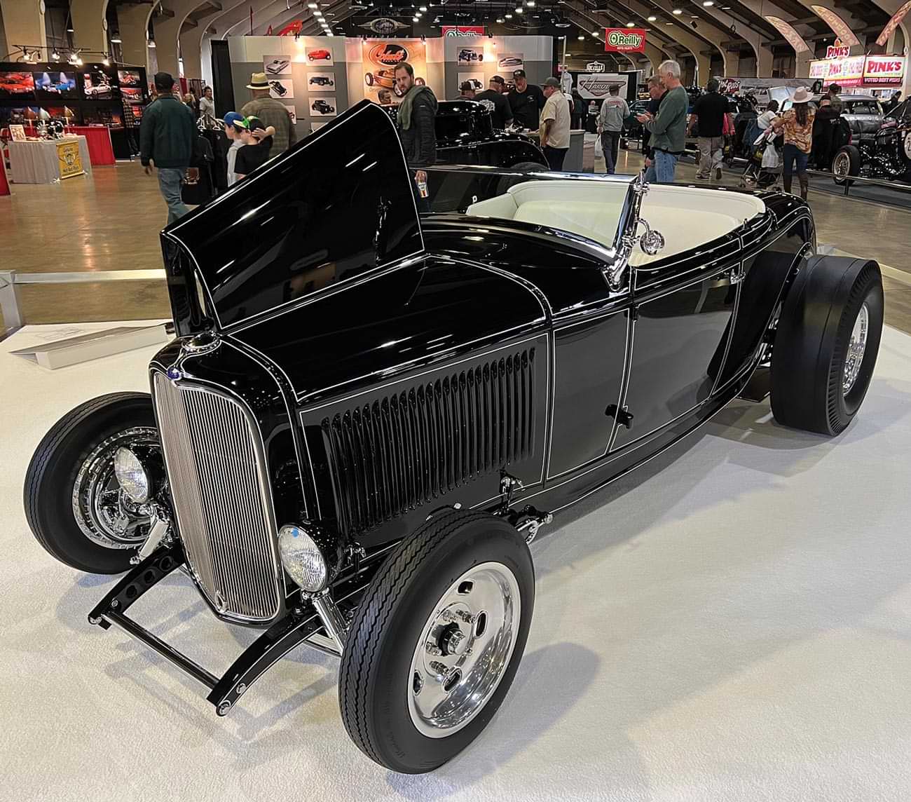 three quarter drivers side view of a black cabriolet ’32 Ford highboy roadster with white outlining