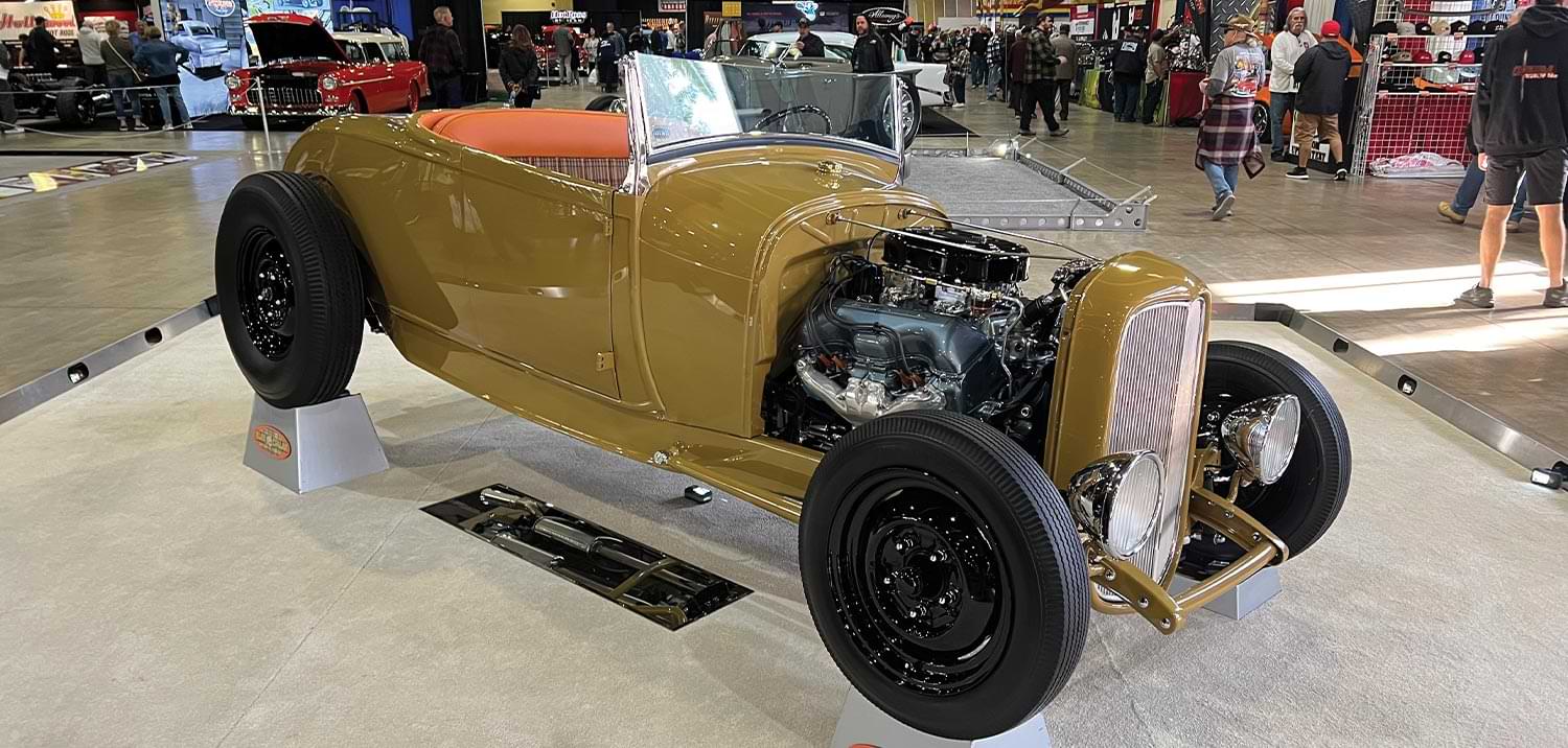 three quarter passenger side view of a flat gold cabriolet ’29 Ford roadster with the hood removed
