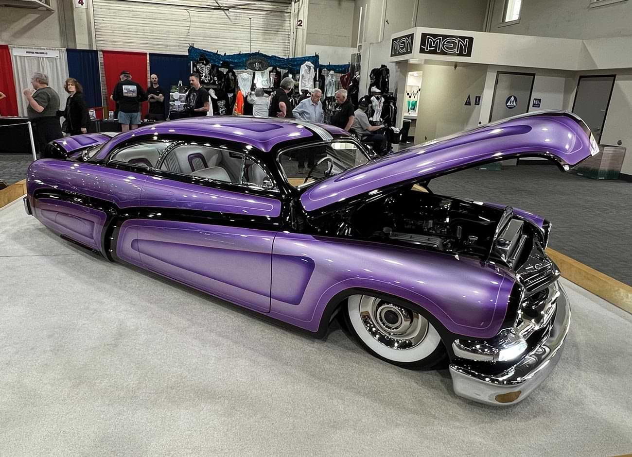 three quarter passenger side view of a ’51 Merc with a a custom purple paint job and its hood lifted