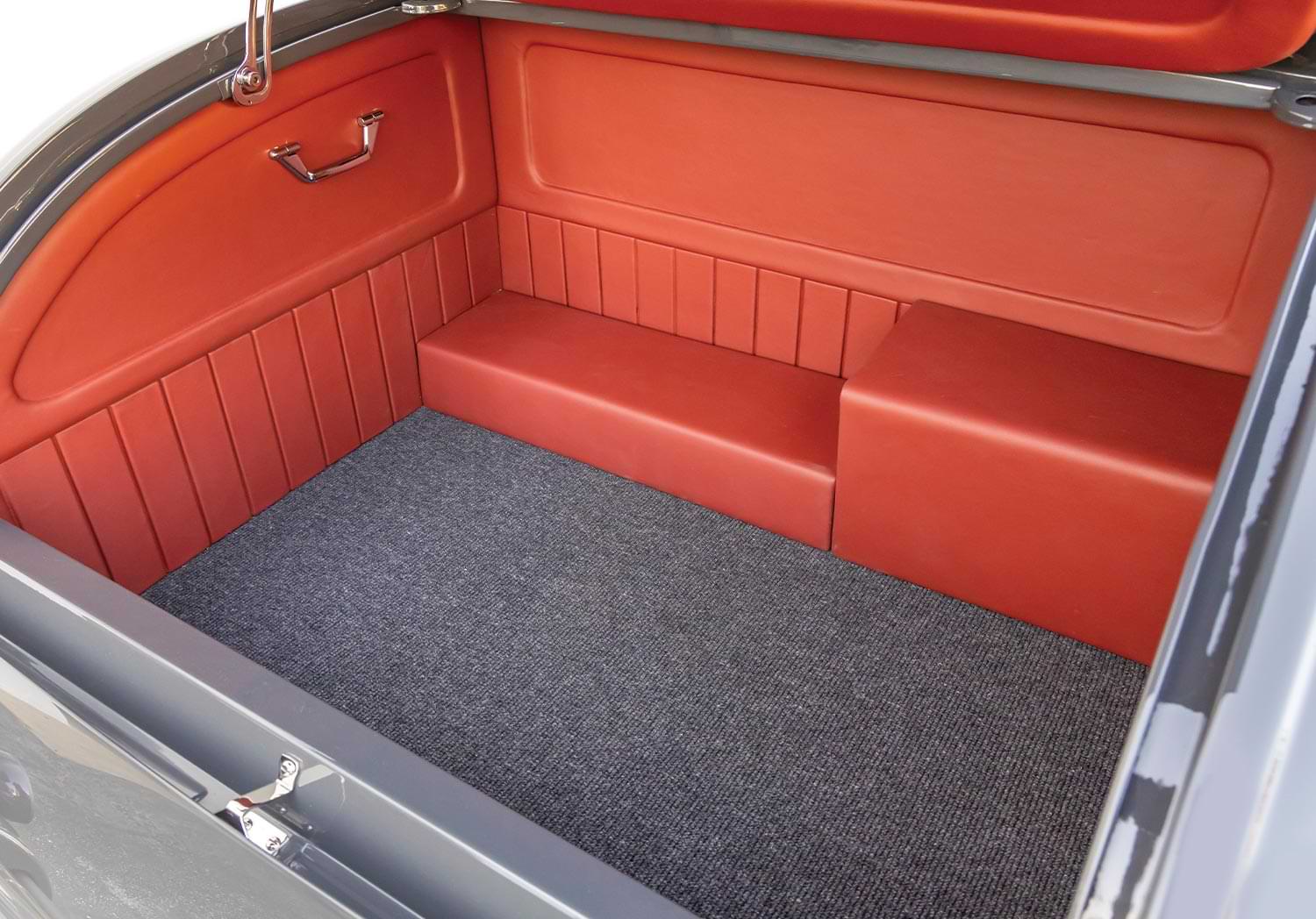 close view of the ’32 Ford roadster's rear gate, featuring carpet flooring and Vermillion Red leather lining