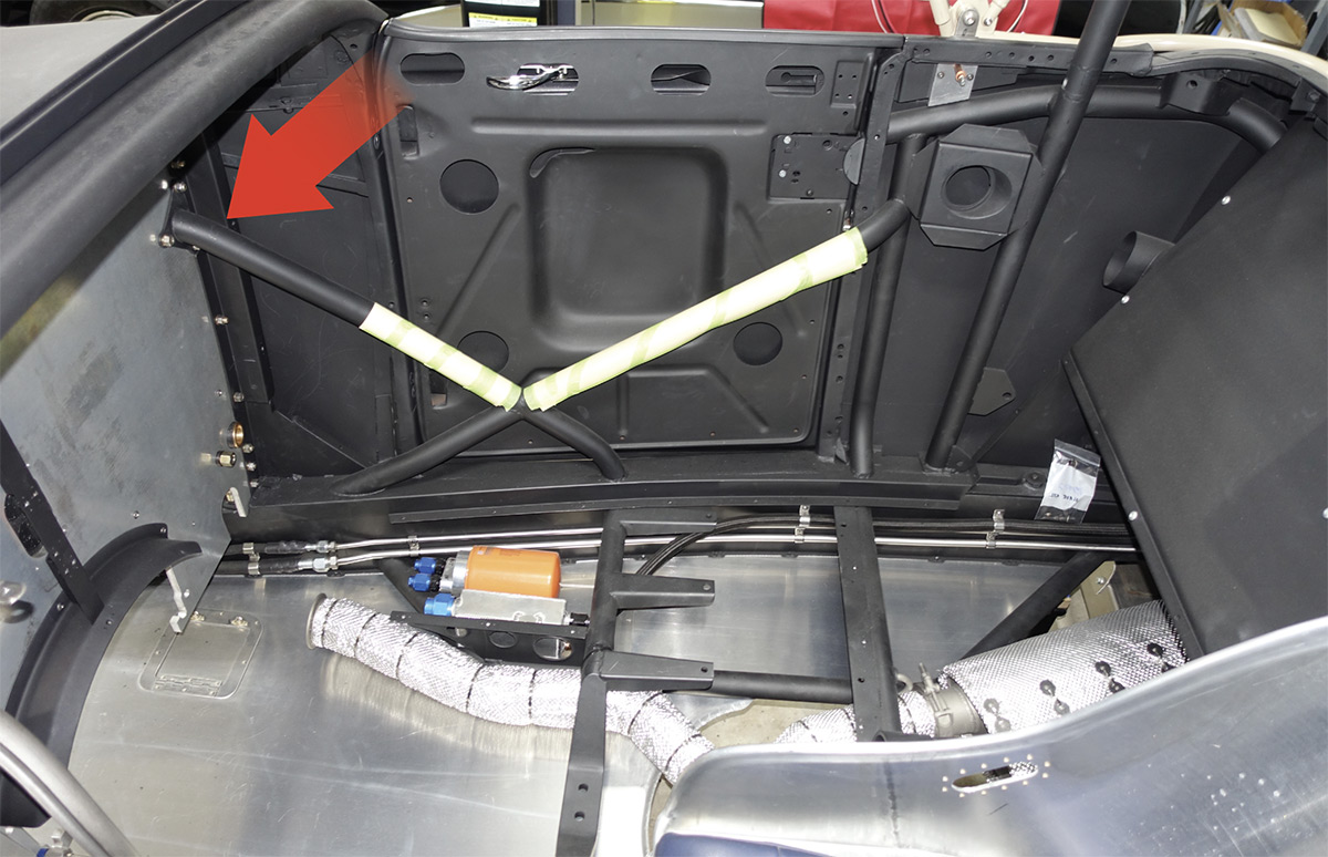 Inside the body is a tubing structure that attaches to the tapered pins in the frame with bolts from below. Note the tube at the top of the firewall (arrow) that ties into the tube on the engine side.