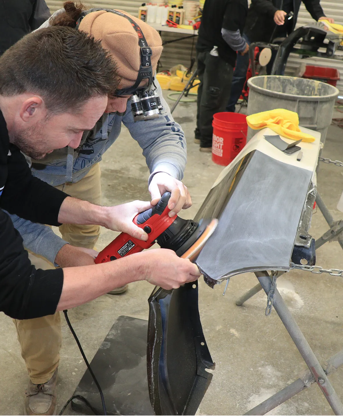 Teaching with a hands-on approach, Jason Killmer instructs the flat angle and amount of compound that must be used to not burn the paint.