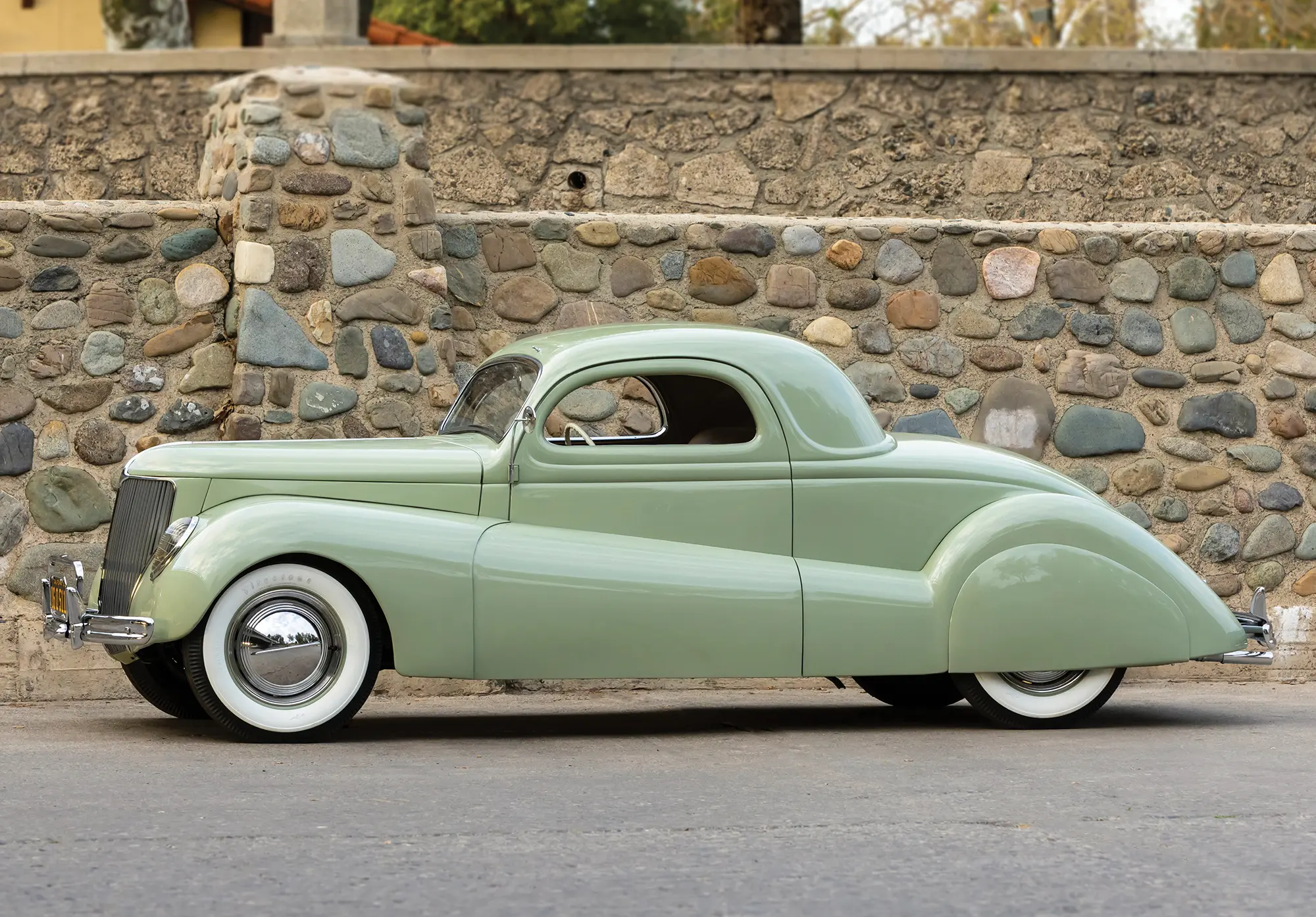 Side view of Coupe in front of stone wall