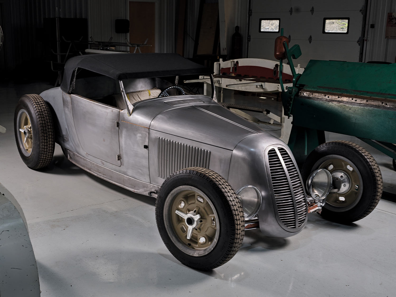 three quarter passenger side view of the paint-bare '27 Ford Highboy Roadster parked in a closed garage