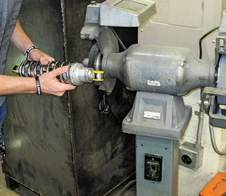 a student dons safety glasses and spins a wire wheel for necessary thread cleanup