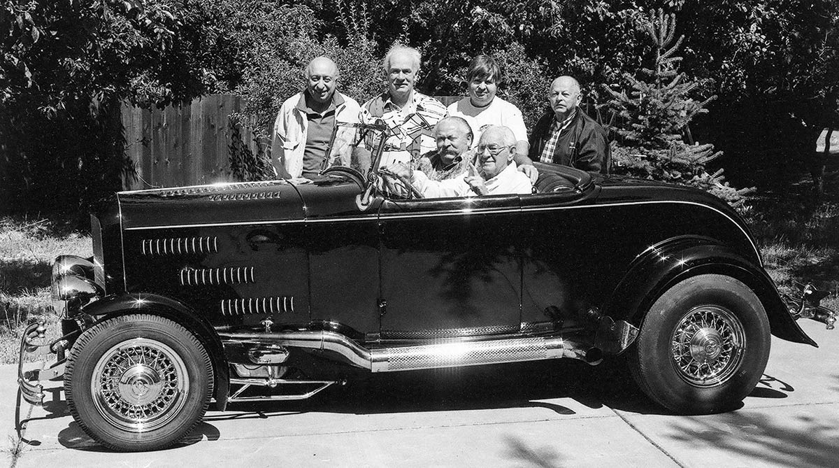 Black & white photograph of The Edelbrock-Bosio-Ladley-Edelbrock roadster car. Fast-forward almost 40 years and the car was the centerpiece in a rare gathering of Northern California rodding figures, all now gone. They include Tommy Hrones (at the wheel); then-owner Jim Ladley, Sonoma; in the passenger seat and standing (left to right) Jack Friedland, Oakland; Jim McLennan, San Francisco; Ed Hegarty, Richmond; and Ed Binggeli (Bing’s Speed Shop), Windsor, CA. Ladley sold the car back to the Edelbrock family soon after this 1995 photo and the roadster was consigned to the Roy Brizio Street Rods in South San Francisco where it was restored to its ’40s and ’50s lakes racer trim.