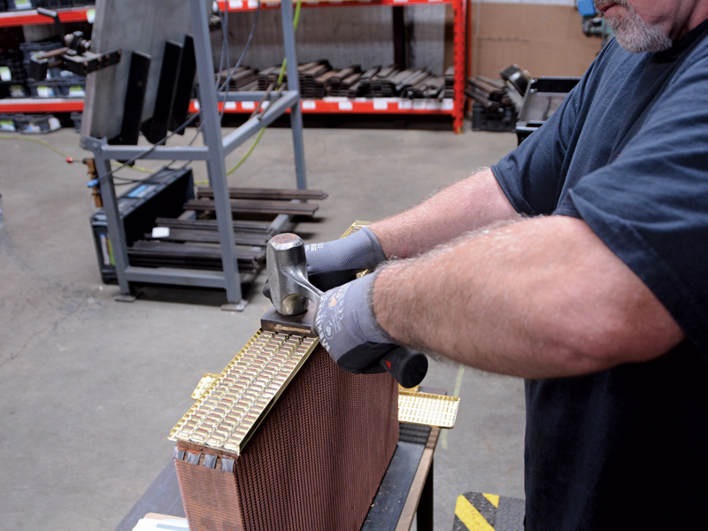 Glenn carefully hammers the header panel onto the core assembly and then uses a special hammer and dolly to securely fasten the header to the core by swedging the tubes evenly across the entire surface.