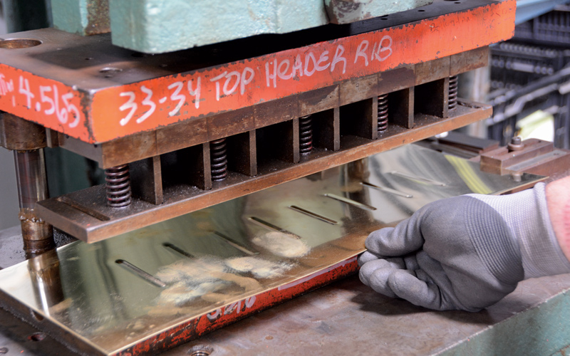 The lower tank starts as a flat sheet of brass and is stamped with strengthening beads before it’s formed.