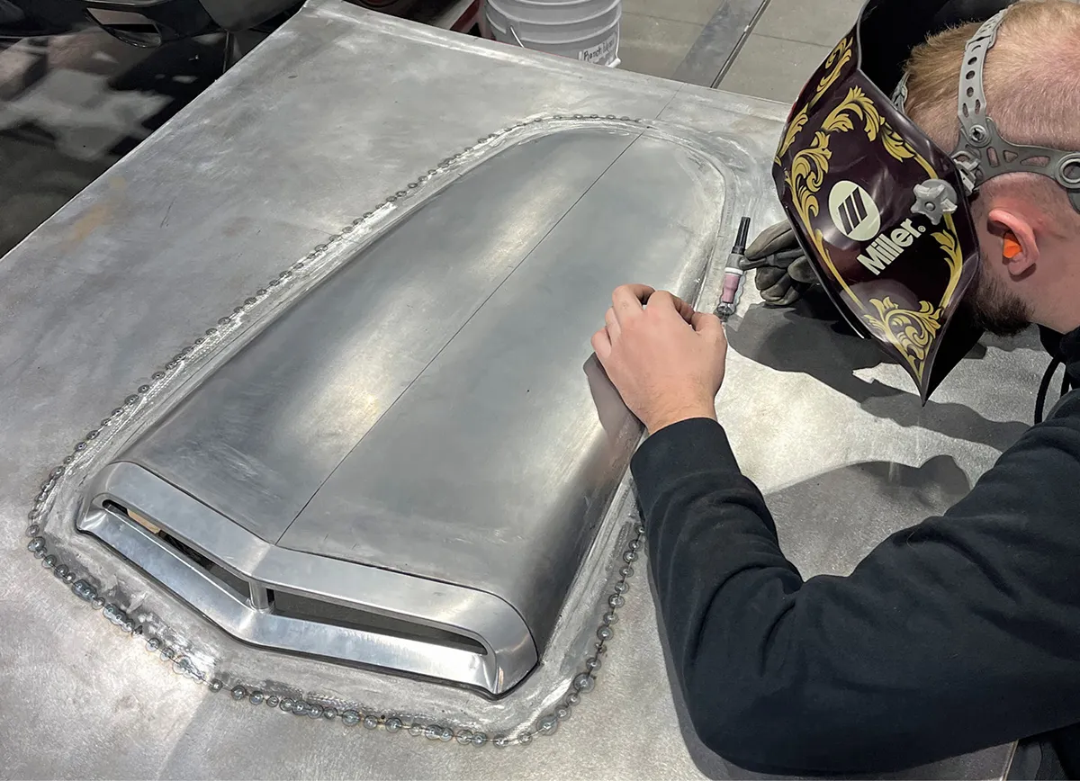 The bezel was CNC machined from billet, fastened to the scoop, and here they are being joined to the hood.