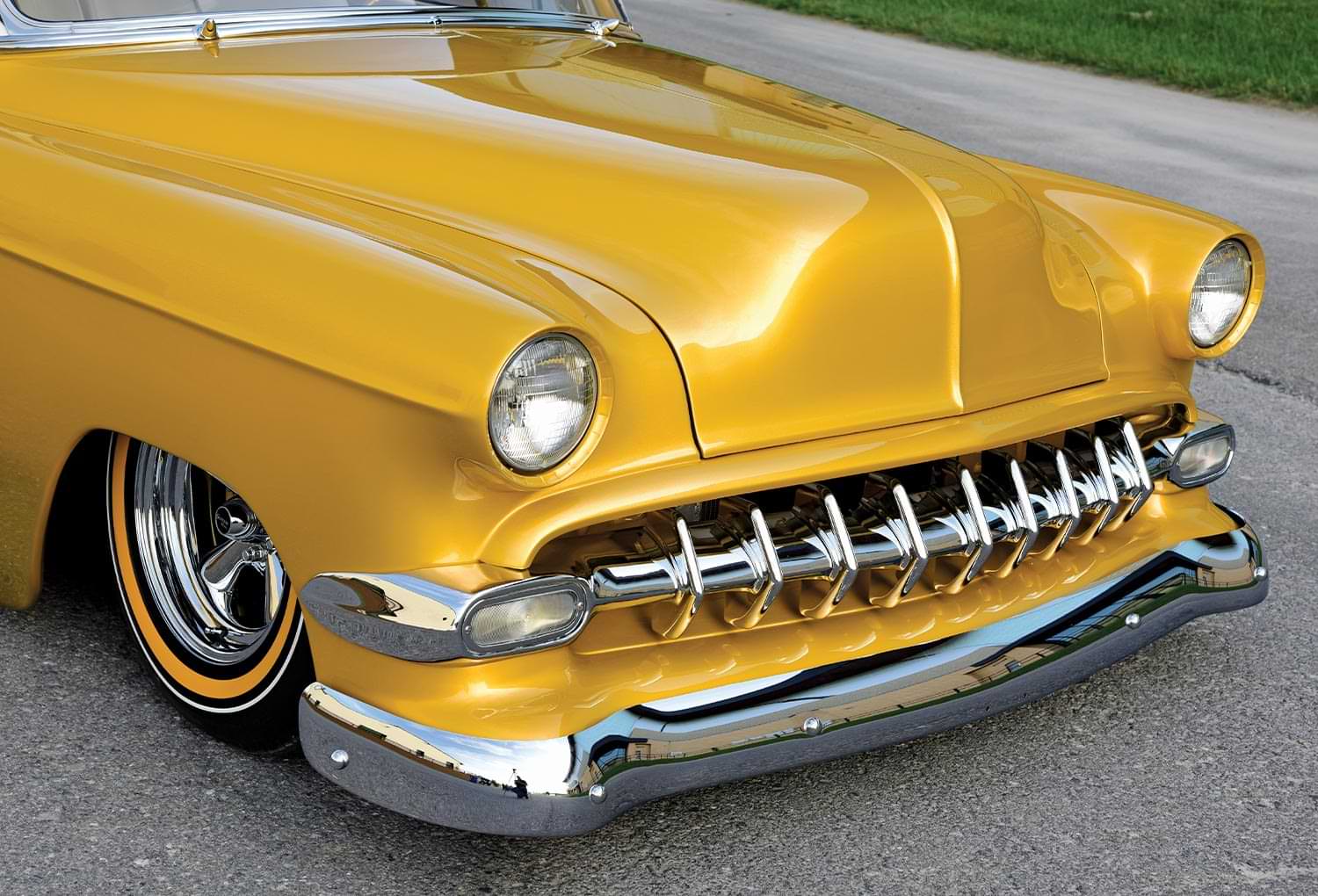 close view of the front section of the custom ’54 Chevy Bel Air including the tire, hood, headlights, grille and front bumper
