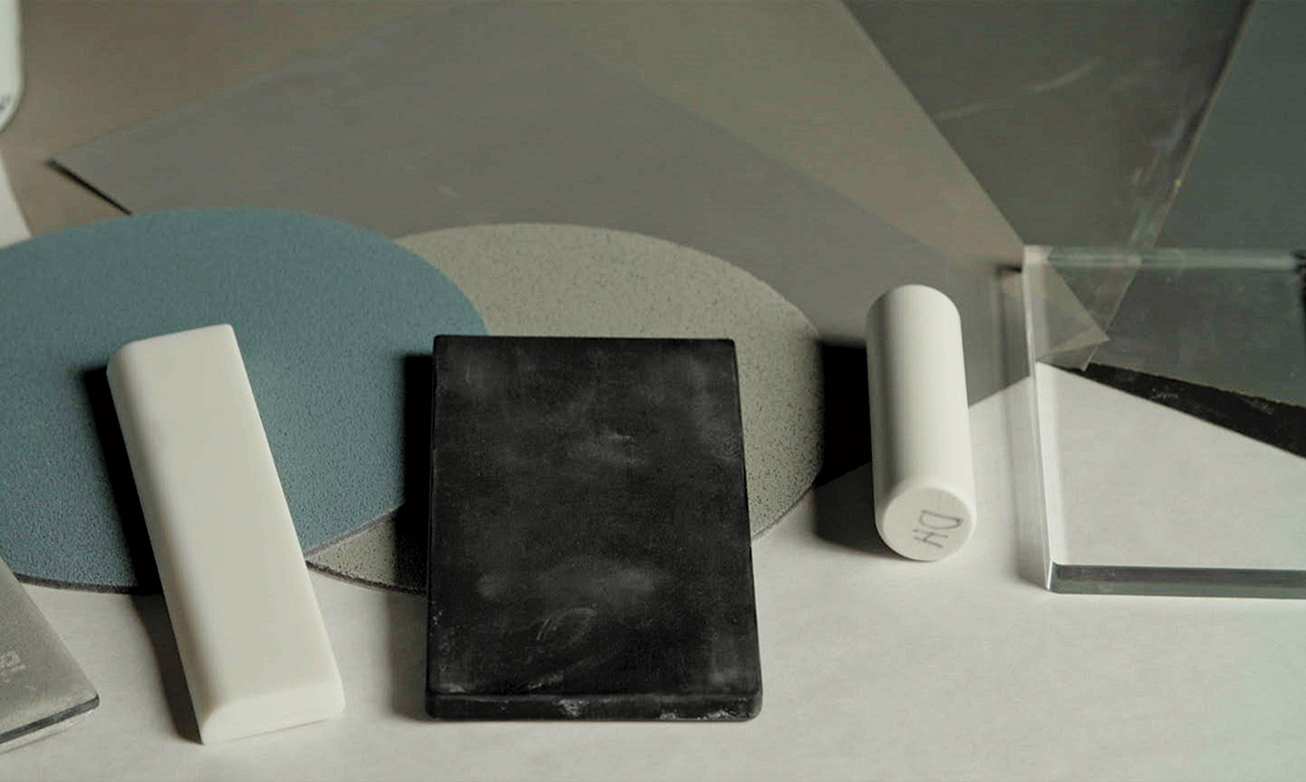 Close-up landscape photograph perspective of polishing objects used (white slim rectangular shape to the left, a black slim rectangular shape in the middle, and a white slim cylinder shape to the right)