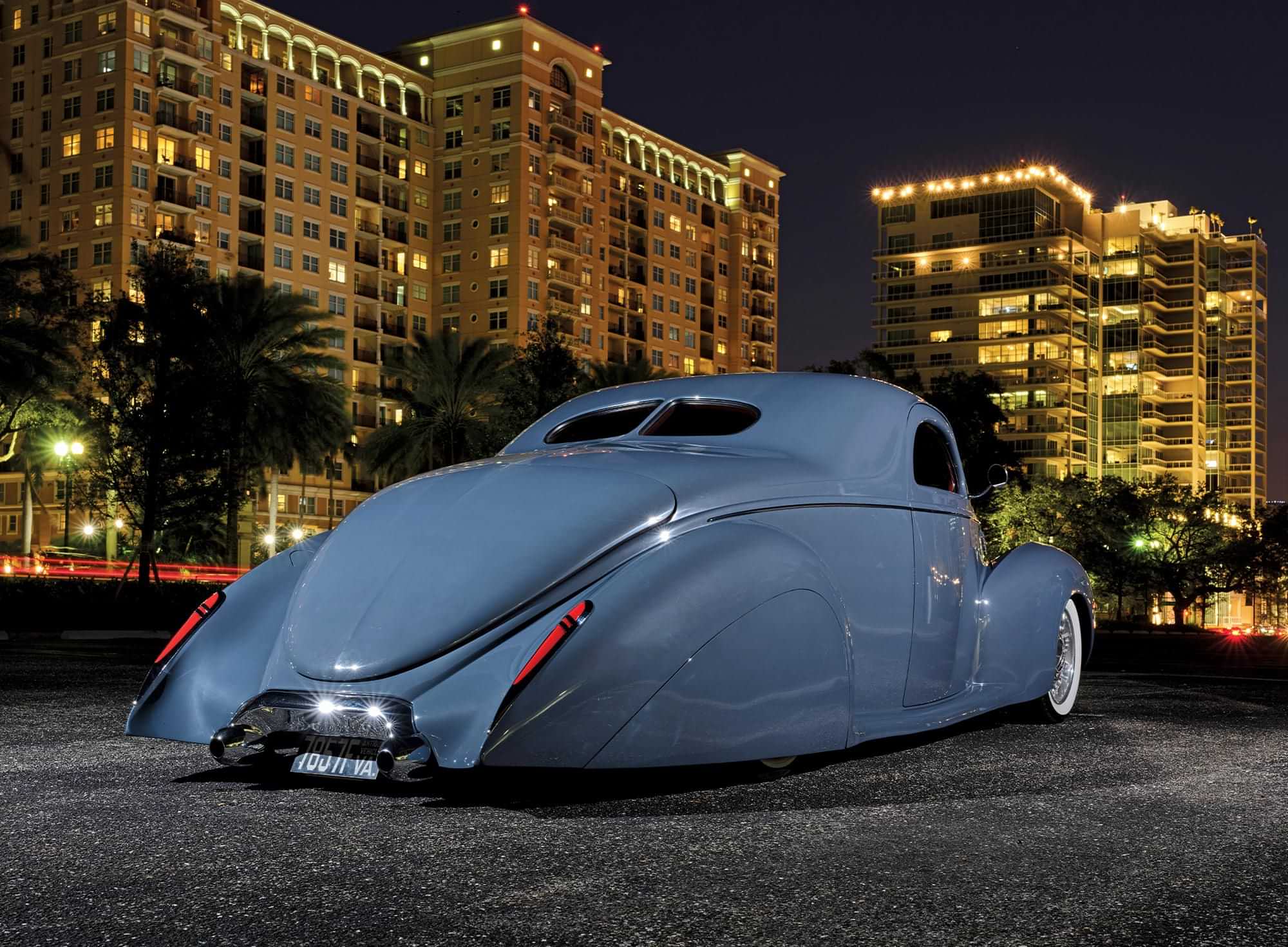 quarter rear view of the graphite blue custom ’38 Lincoln Zephyr photographed against a night sky lit by highrise buildings