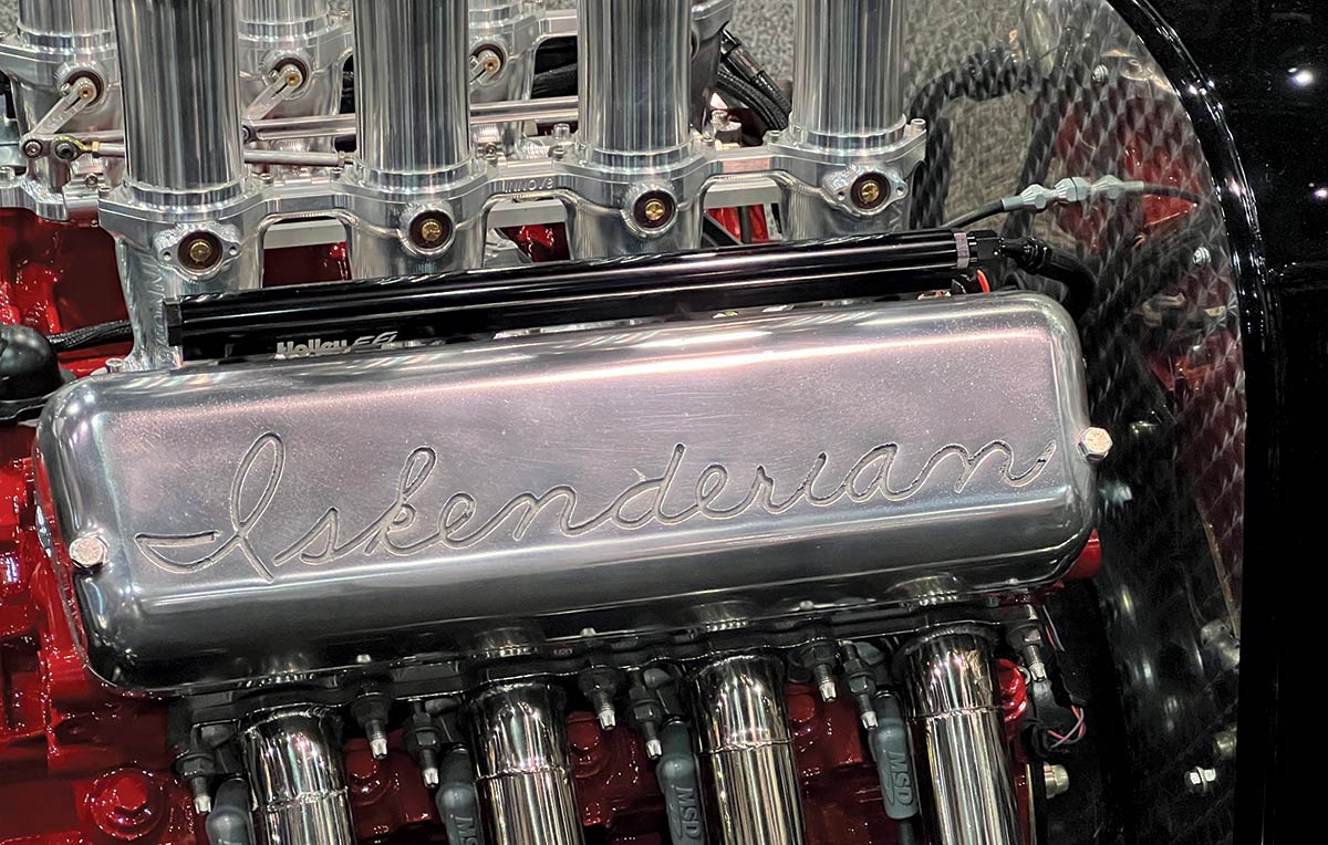 Landscape photograph perspective of the hand engraved cursive lettering etched into the one-of-a-kind cast-aluminum valve covers that reads Iskenderian; Dennis was the one responsible for casting the one-of-a-kind valve covers complete with the cursive Iskenderian name imprinted. Nick Taylor of Nickky Bobby Inc. came up with the adapters that allowed the special valve covers to be used with the Ford V-8.