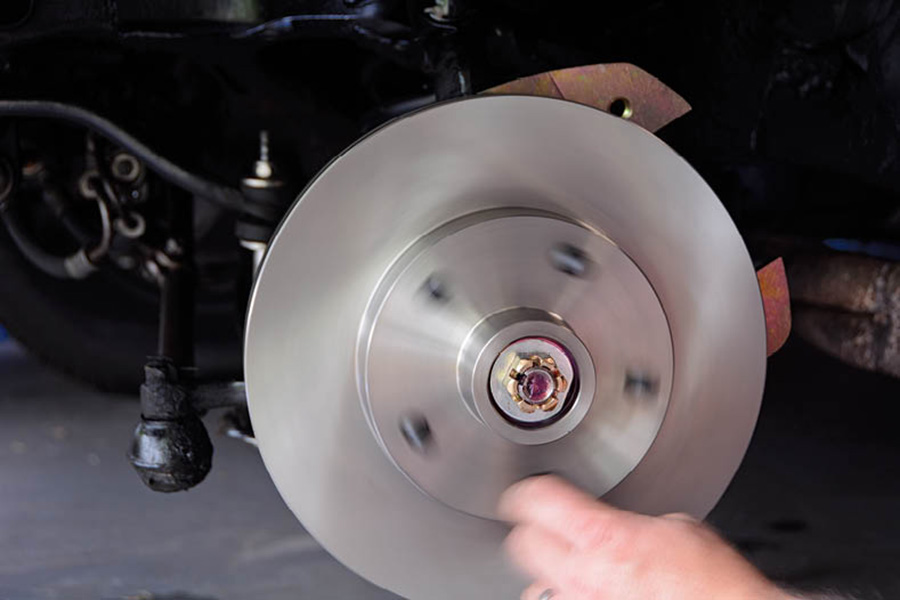 To adjust the wheel bearing, we tighten the castle nut until we start to feel tension. Then, spin the rotor a few times to make sure the bearing is seated, and back it off until the cotter pin hole is lined up with the castle nut.