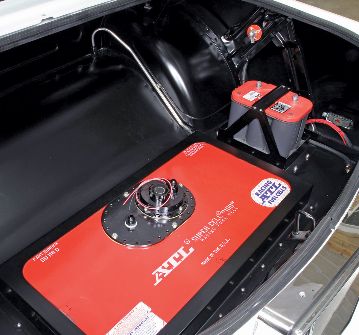 Portrait close-up angle view of the red/black ATL Super Cell 100 Series Racing Fuel Cell engine part number SU 118 D inside the vintage 1987 Pontiac Grand Prix (Project: G-Force One) white car