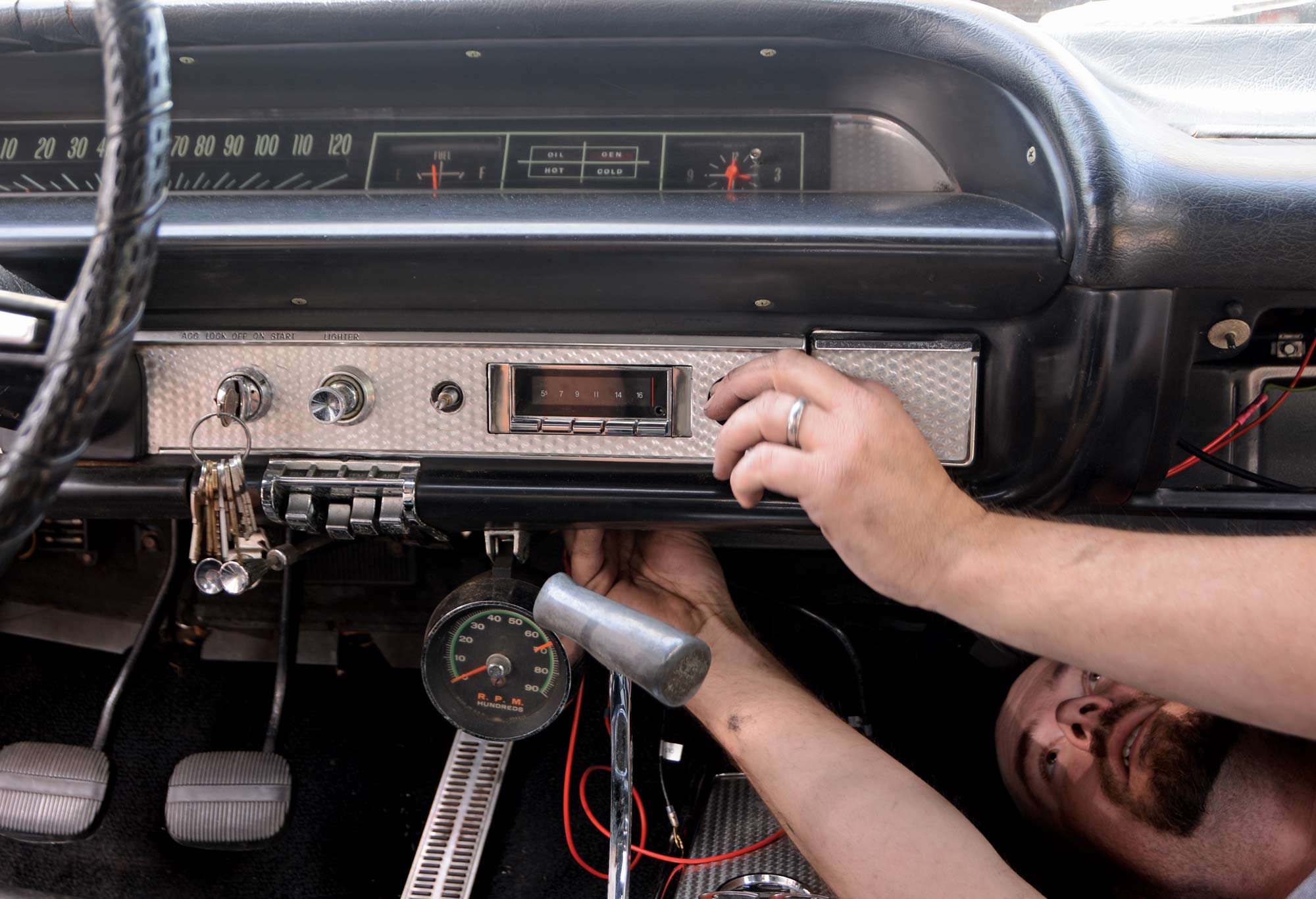 Man working on installing a new stereo under the dashboard