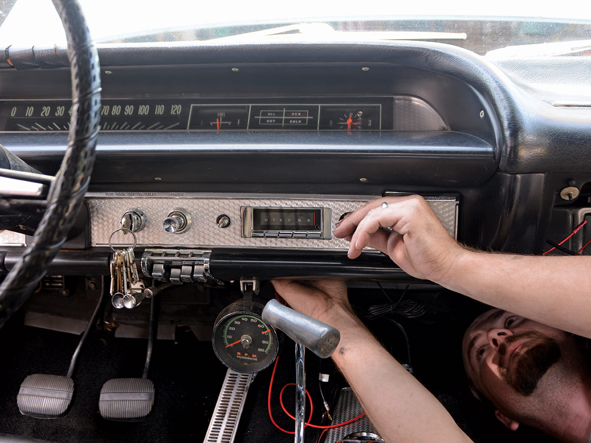 Man working on installing a new stereo under the dashboard