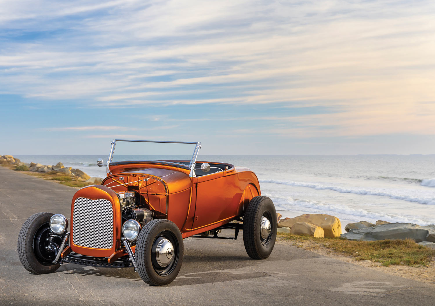 orange ’29 Ford Model A roadster parked near the beach