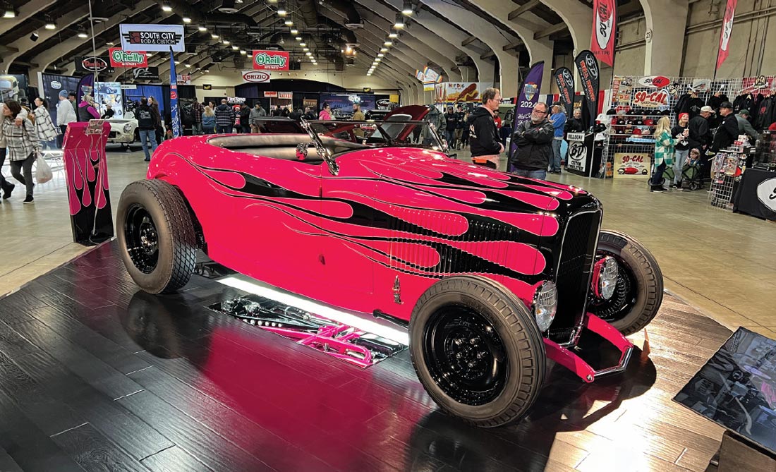 passenger side view of a pink ’32 Ford highboy roadster with black flames