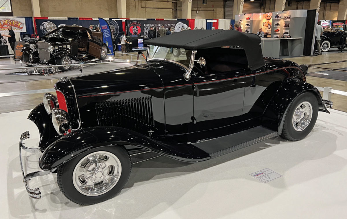 driver side of a black ’32 Ford roadster with a black top an red accents