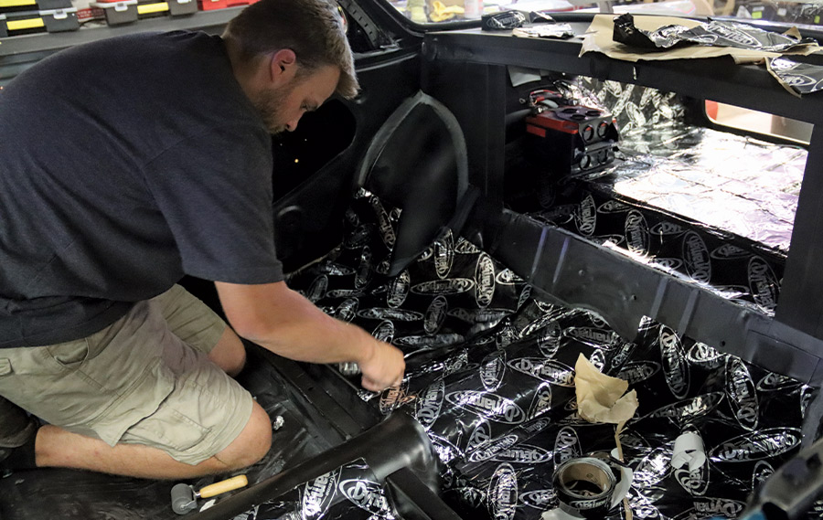 Nick McMath laying down a layer of Dynamat int he interior of the car