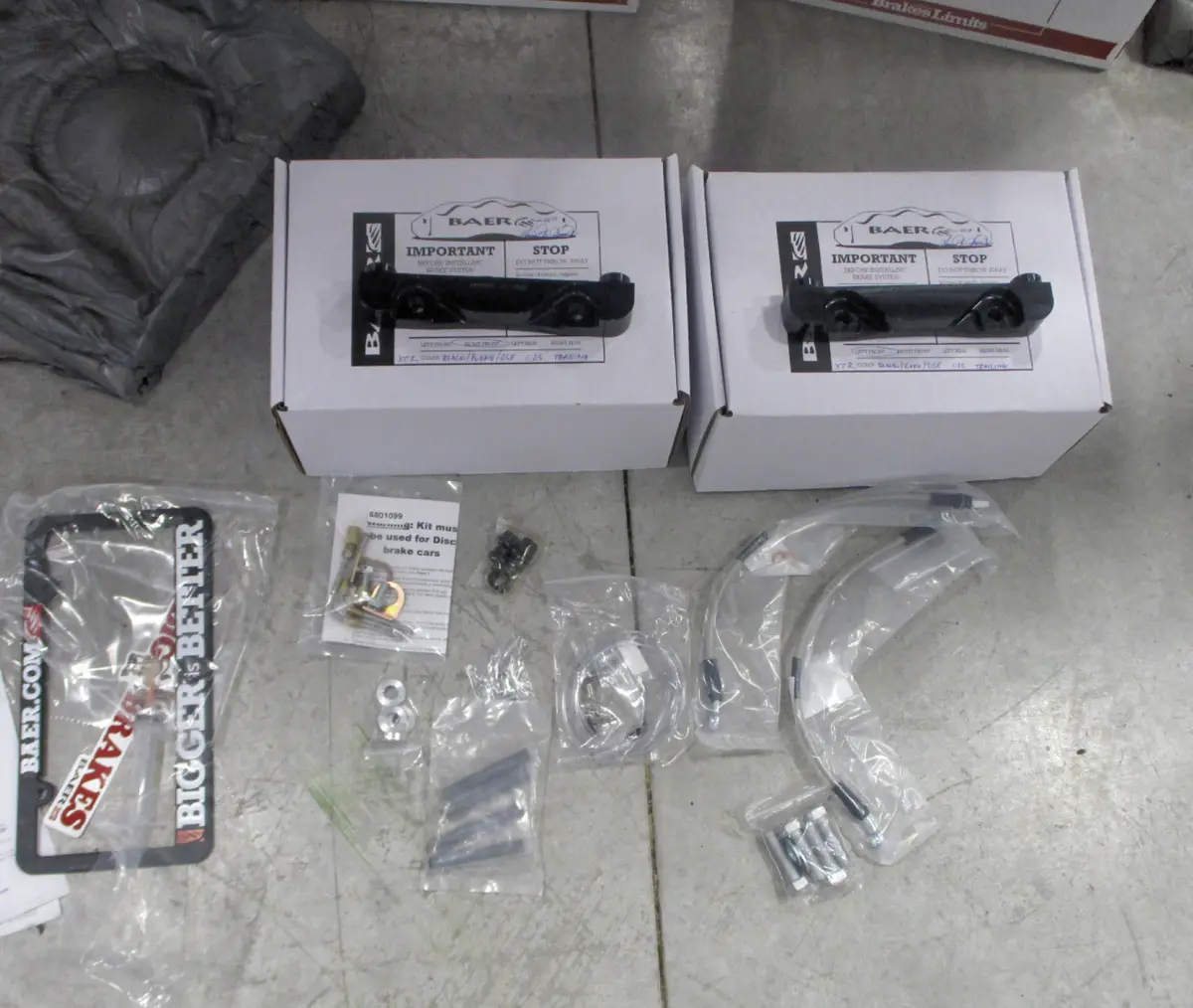 top view of the Baer/DSE Extreme+ front brake kit and all its included parts, including mounting brackets, braided brake hoses, and detailed instructions