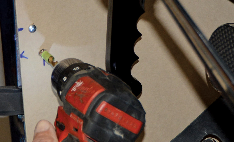 drill with masking tape around the drill bit creating a hole in the panelboard